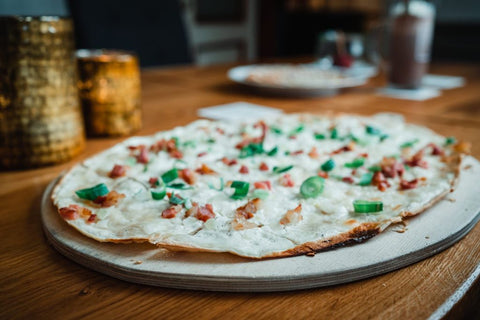 Frischer duftender Flammkucken mit Creme Fraiche, Lauchzwiebeln und Speck