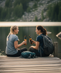 2 Frauen sitzen auf einem Steg an einem See im Sauerland und trinken Bier aus der Flasche